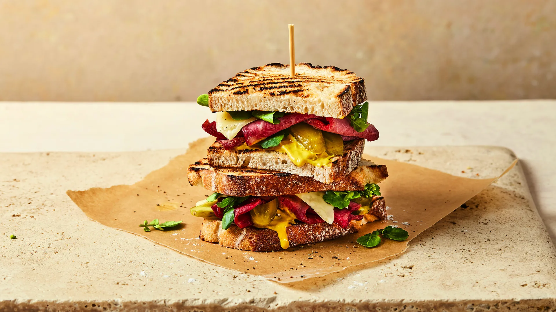 A close-up image of a Hovis®  White Sourdough sandwich with roast beef, cheese, spinach and pickles spilling out. 
