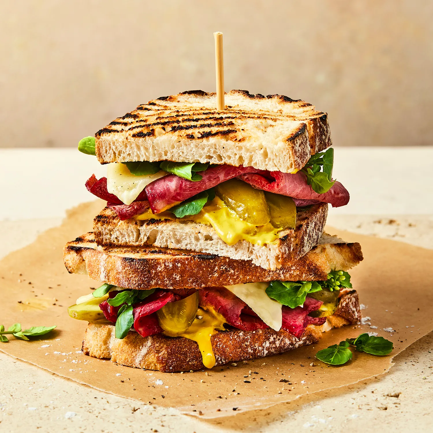 A close-up image of a Hovis®  White Sourdough sandwich with roast beef, cheese, spinach and pickles spilling out. 