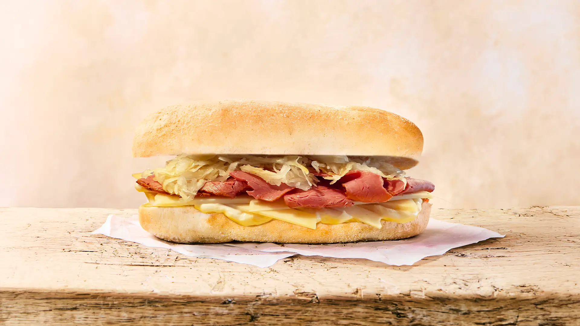 A  Reuben Sandwich sits on a white cloth on a wooden table