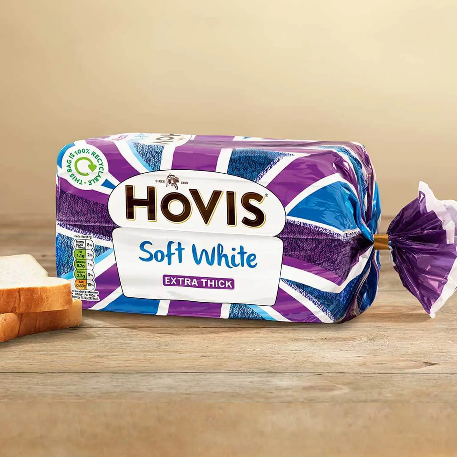 Hovis Soft White Extra Thick Sliced bread against a beige background, on a wooden table, with two stacked slices on the left.