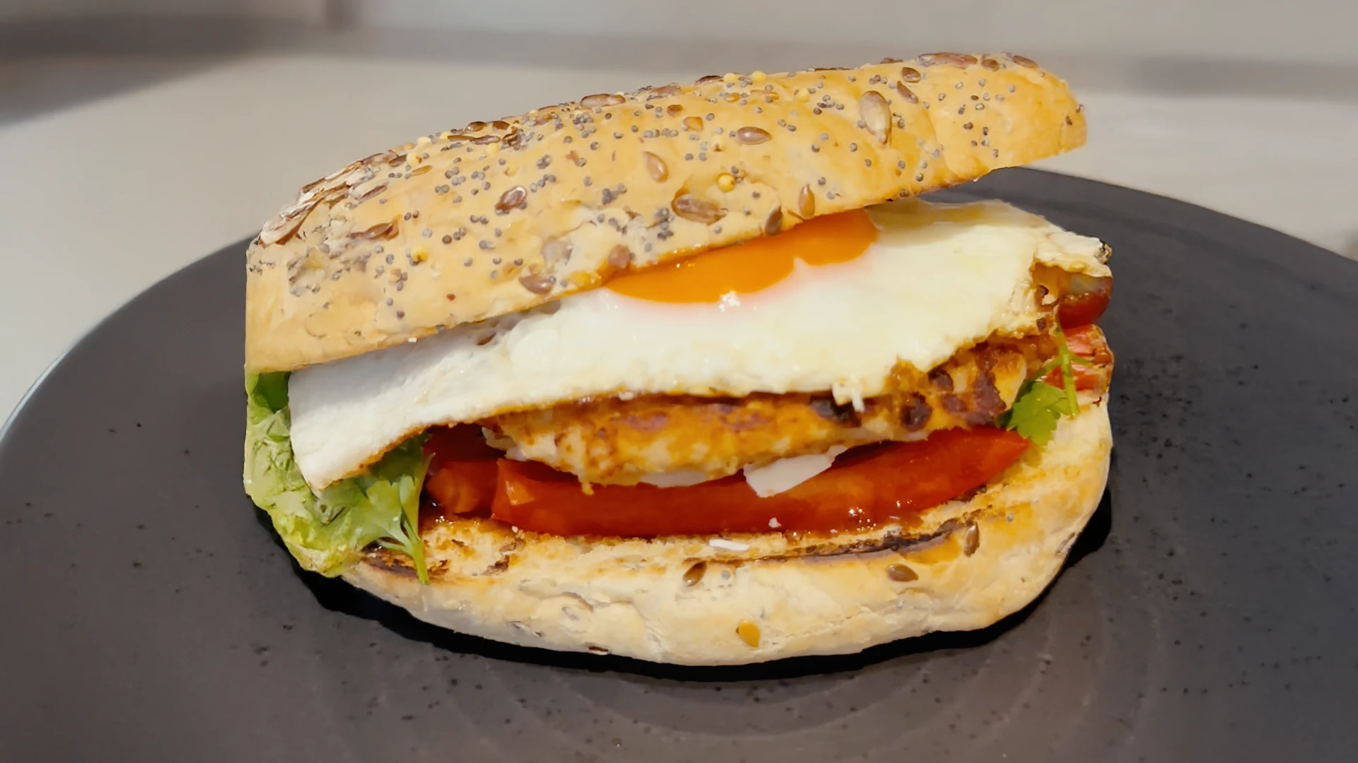An egg, sausage, red peppers and lettuce in a Hovis Deli Roll on a plate.
