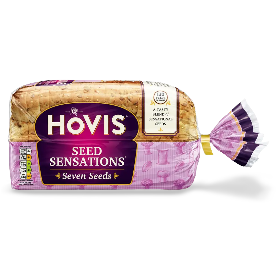 Hovis Seed Sensations Original bread with a subtle shadow under it. The packaging is half transparent and half pink, decorated with images of flour, a chef's hat, seeds and wheat.