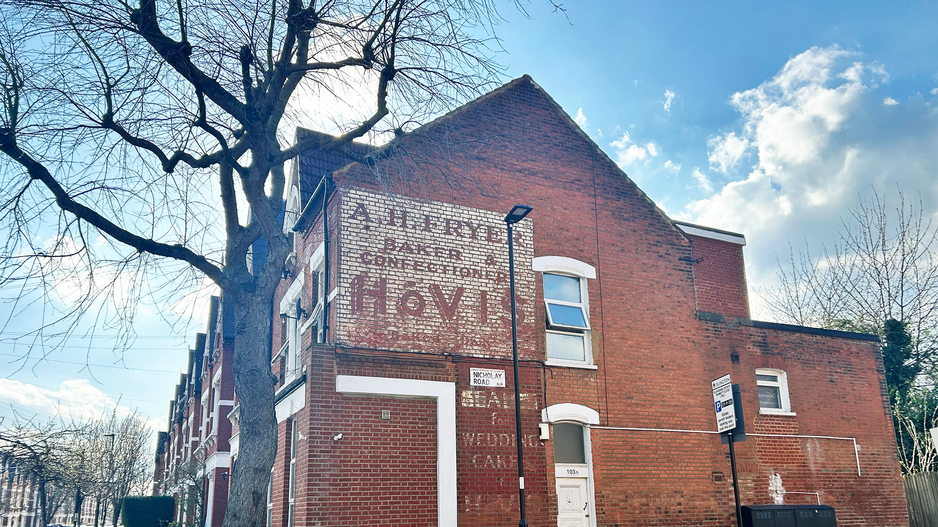 A Hovis advertisement painted on a brick wall, also known as a Ghost Sign. In the faded lettering it reads A.H. Fryer. Baker & confectioneries. In bigger type, Hovis